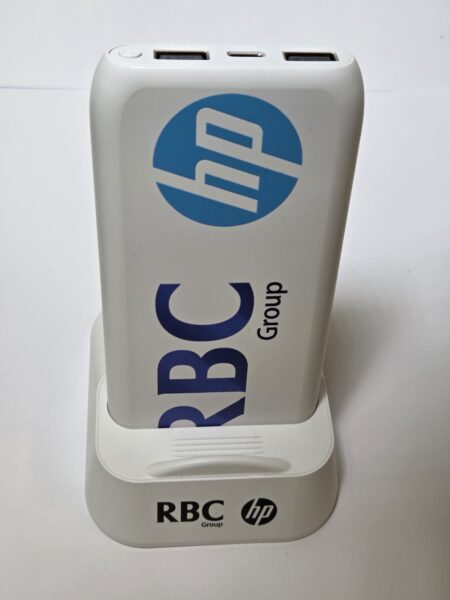 White power bank with RBC Group and HP logos, in a dock—ideal for corporate gifts.