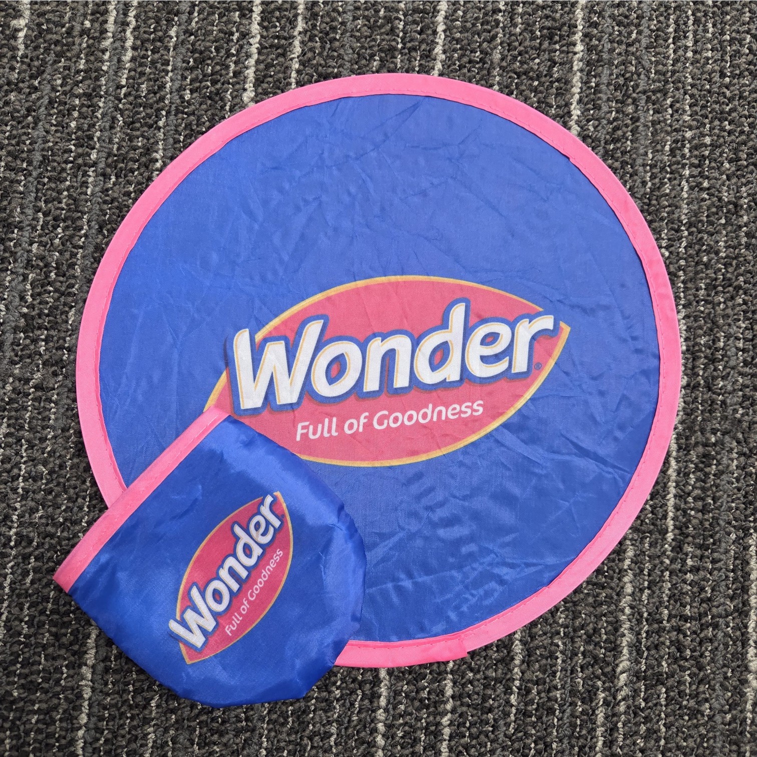 Blue and pink Wonder branding sign with Full of Goodness text on a carpeted floor.
