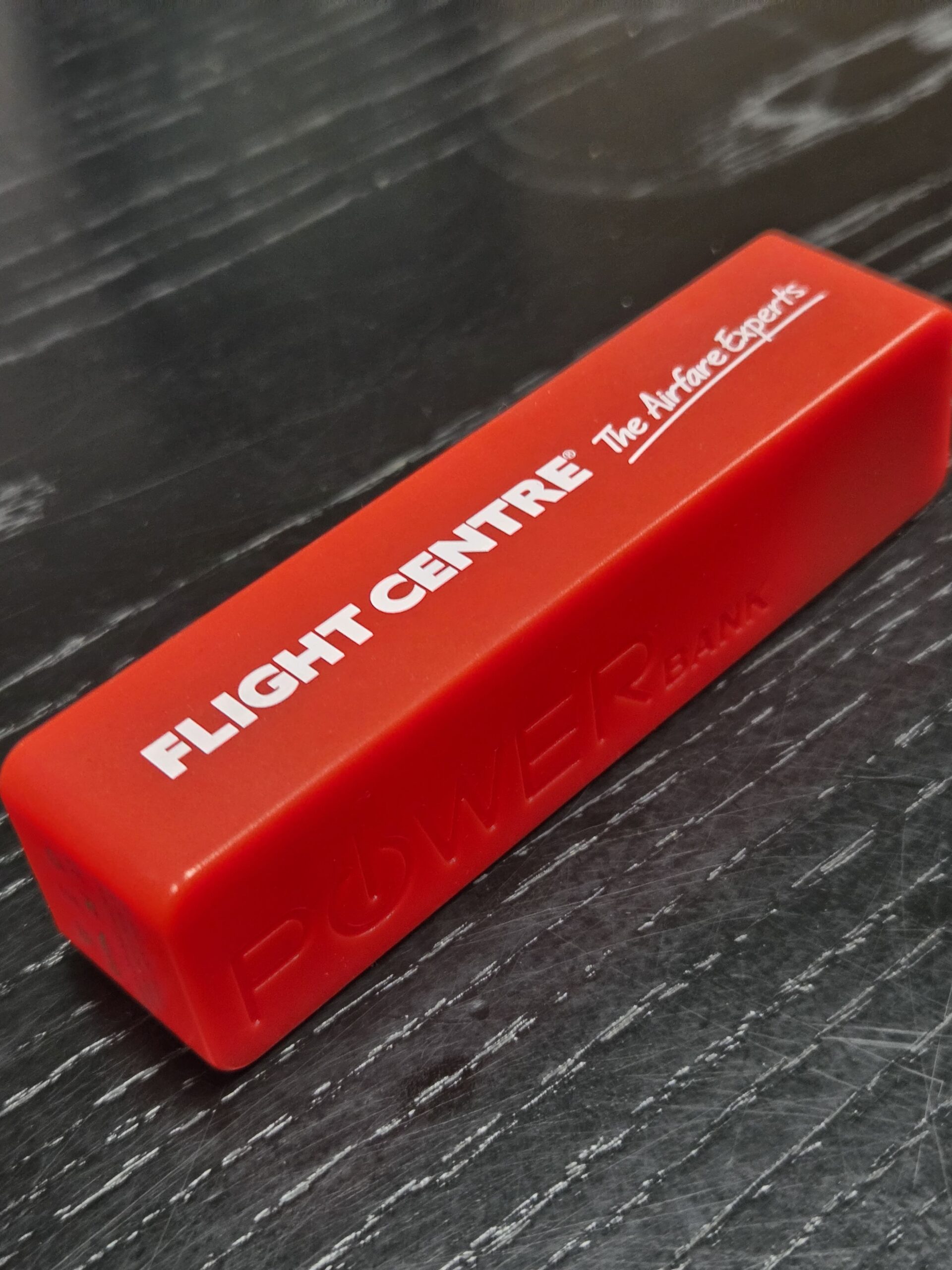 Red rectangular power bank with Flight Centre branding, perfect for airfare experts on the go.