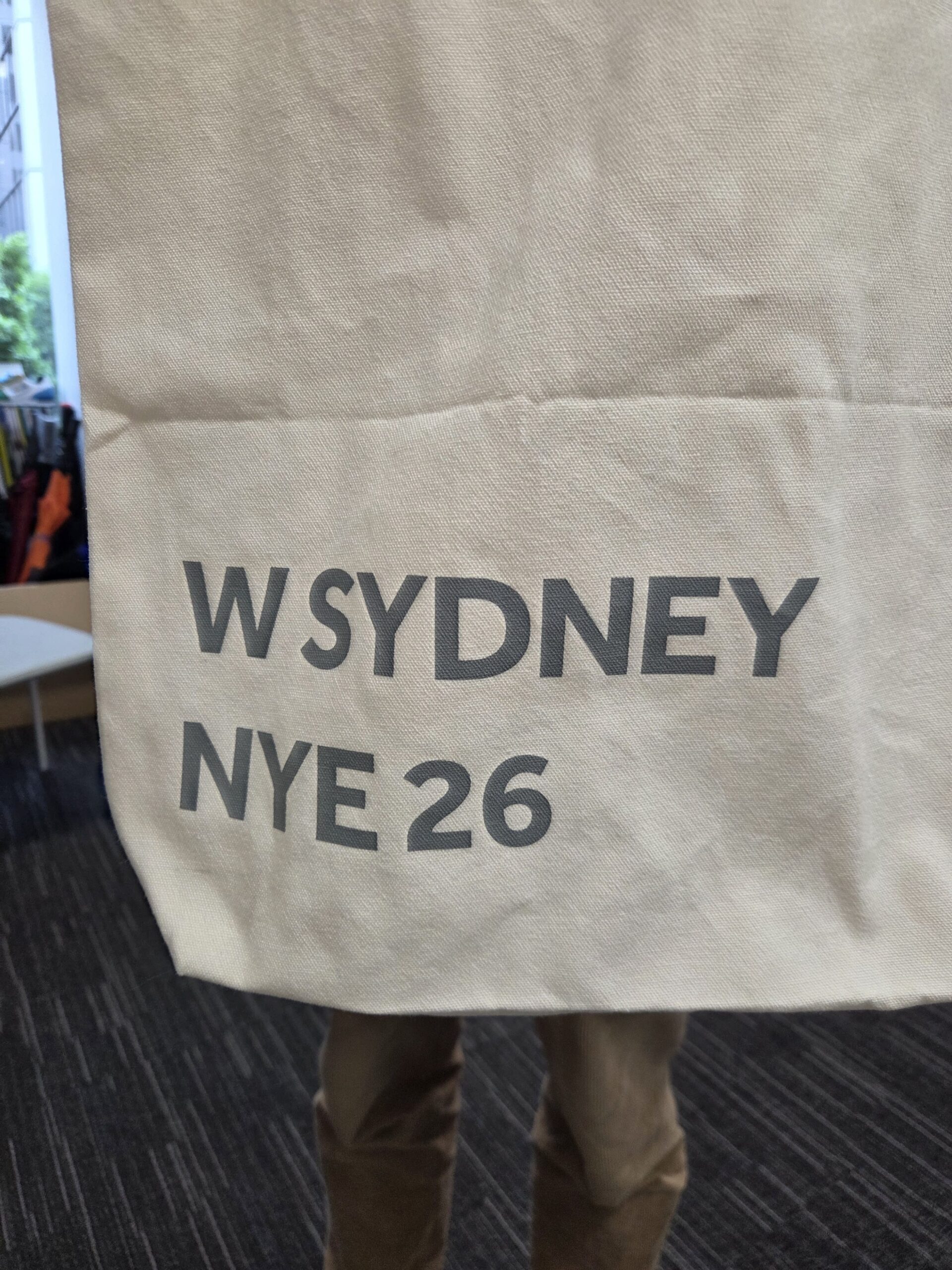 Beige tote bag with W Sydney NYE 2026 in gray letters.