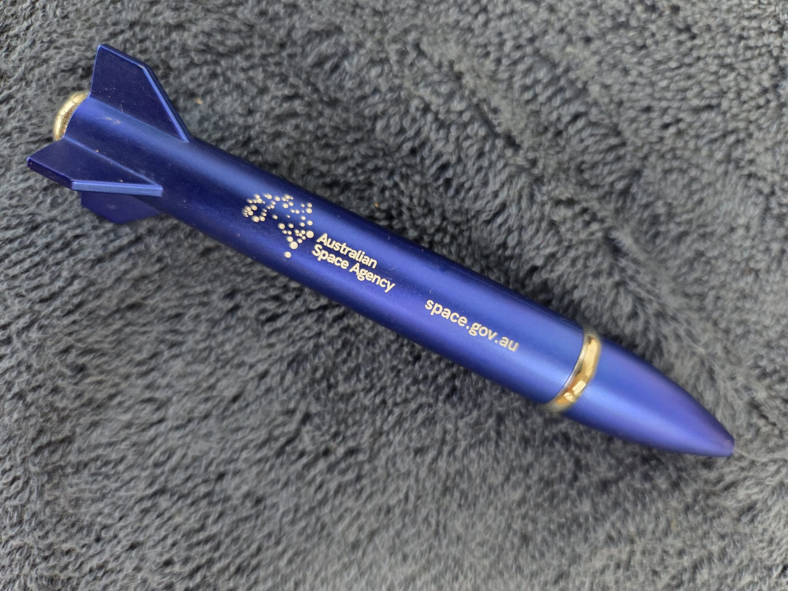 A rocket-shaped blue pen with Australian space agency logo and website printed on it.