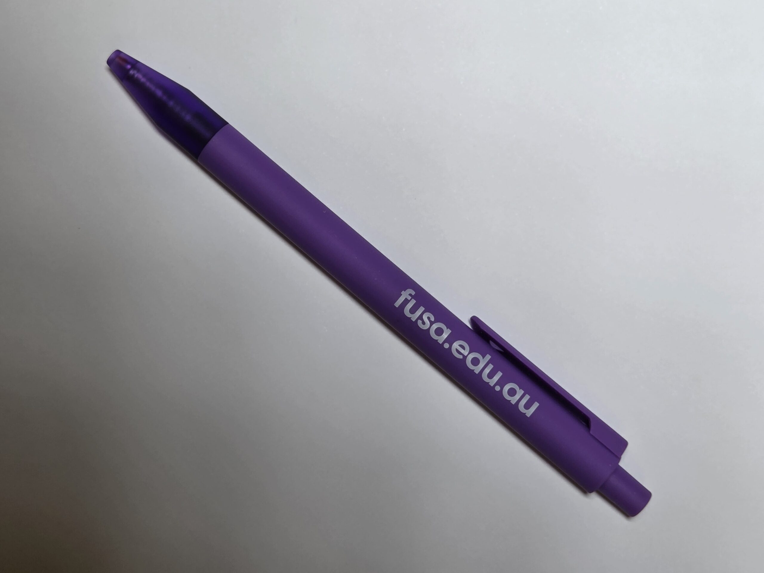 A purple pen with fusa.edu.au and Flinders University printed on its side, on a white surface.