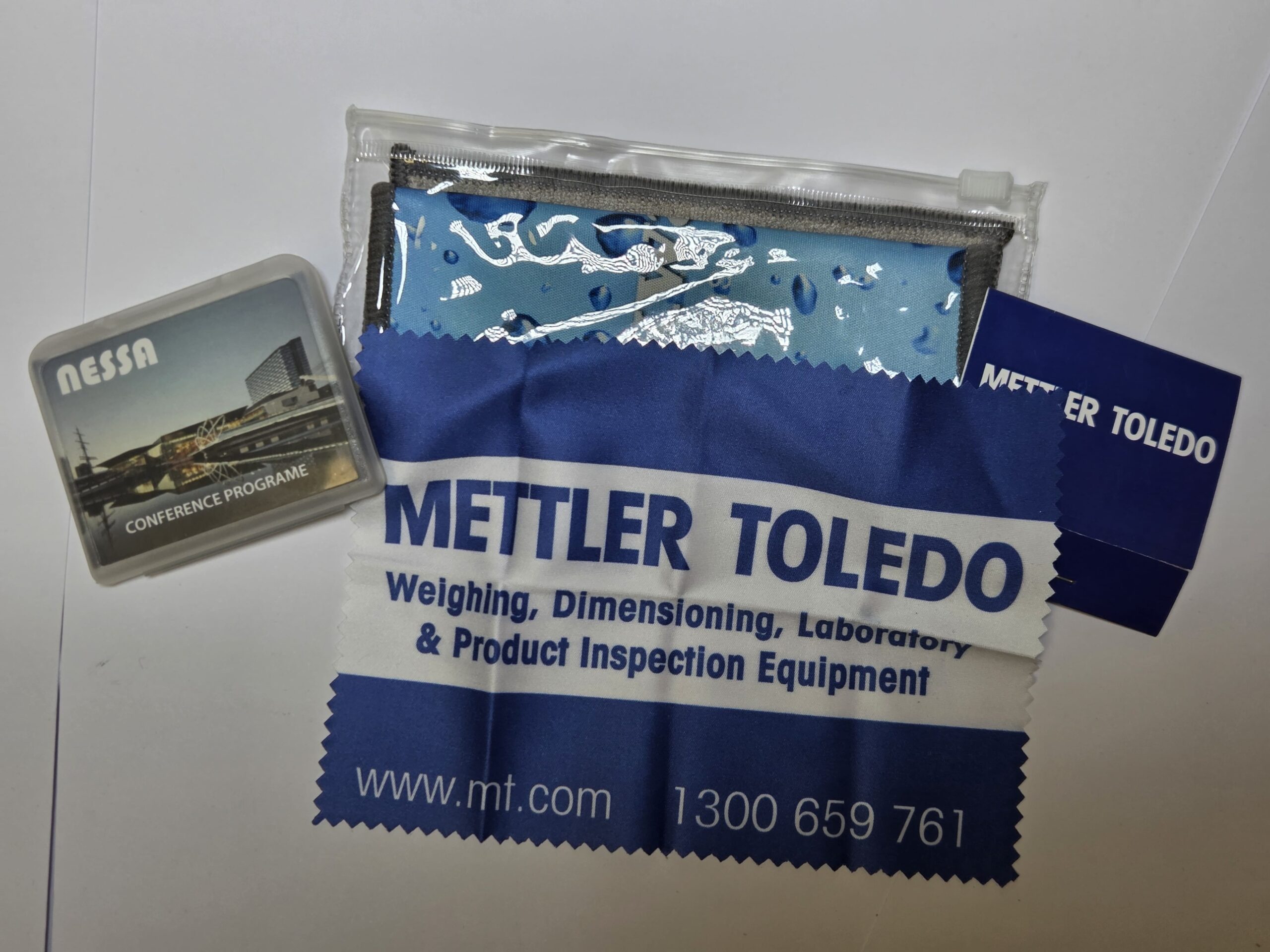 Mettler Toledo onboarding kits with microfibre cloths, conference programme, and zip pouch.