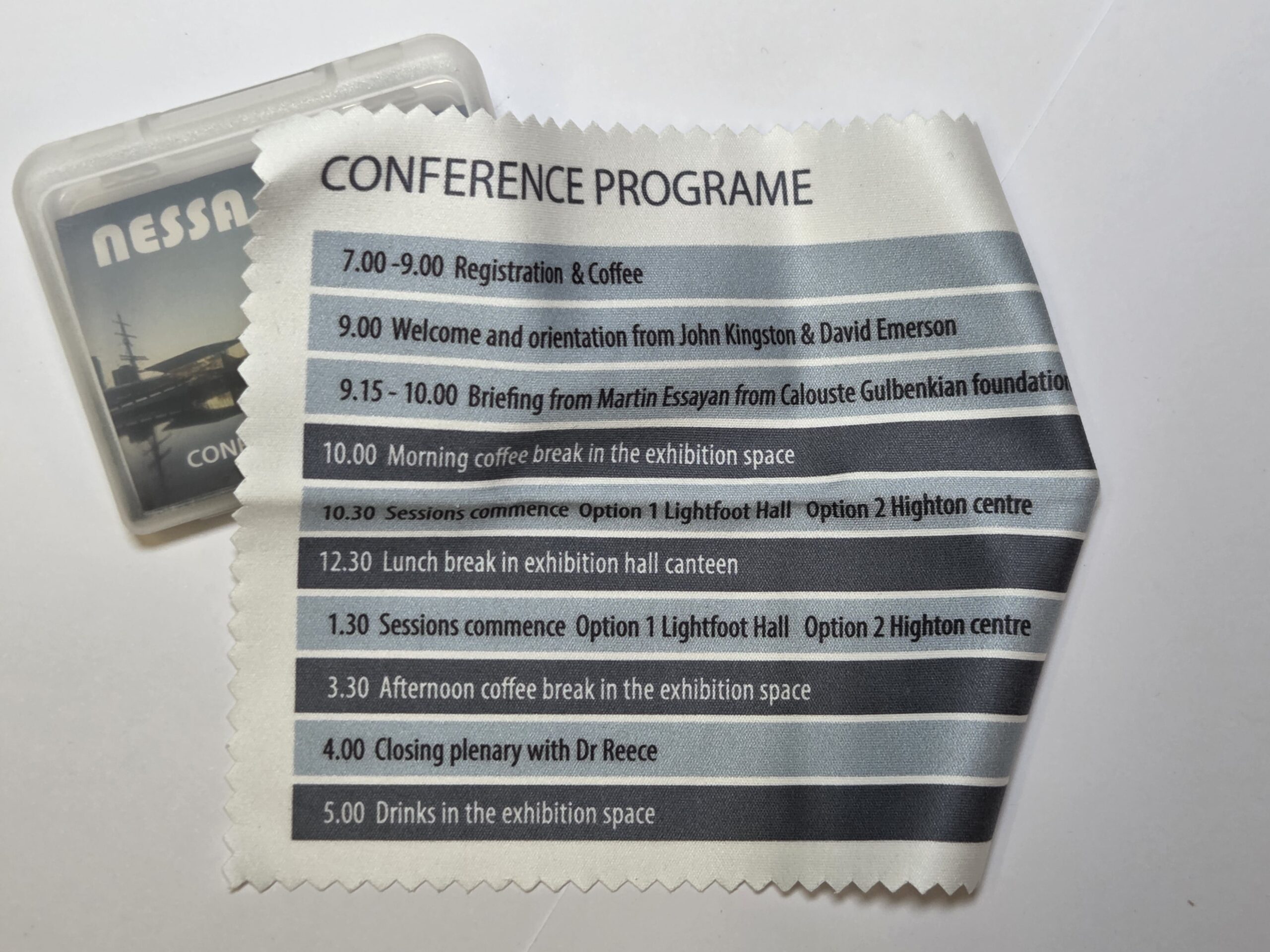 Conference programme on a microfibre cloth listing event times, with a badge partly visible.