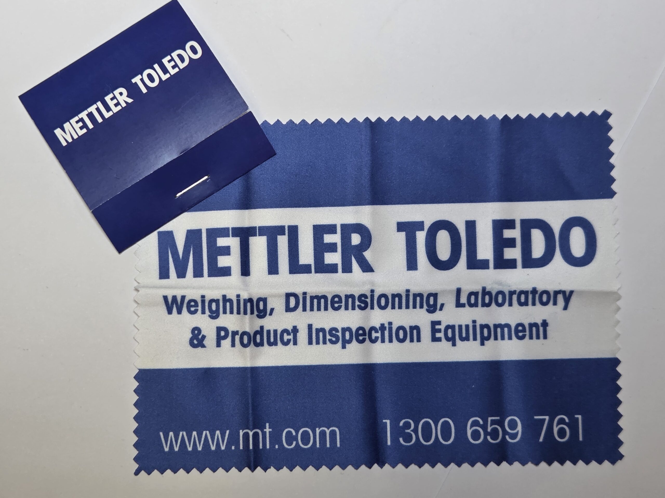 Blue microfibre cloth and matchbook with METTLER TOLEDO branding and white contact info.