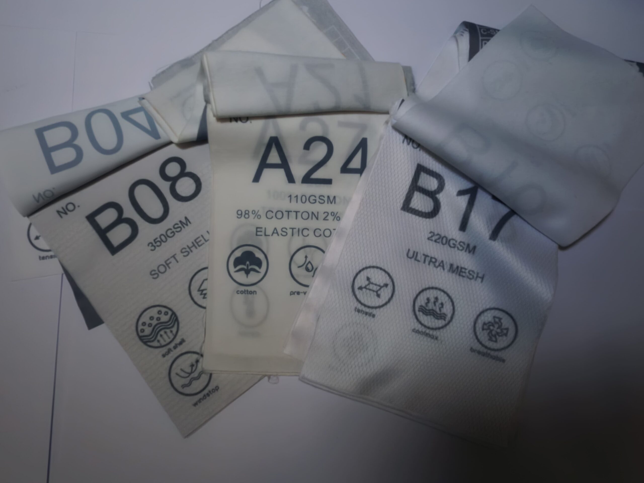 Several fabric samples with showroom codes and material details are spread on a flat surface.