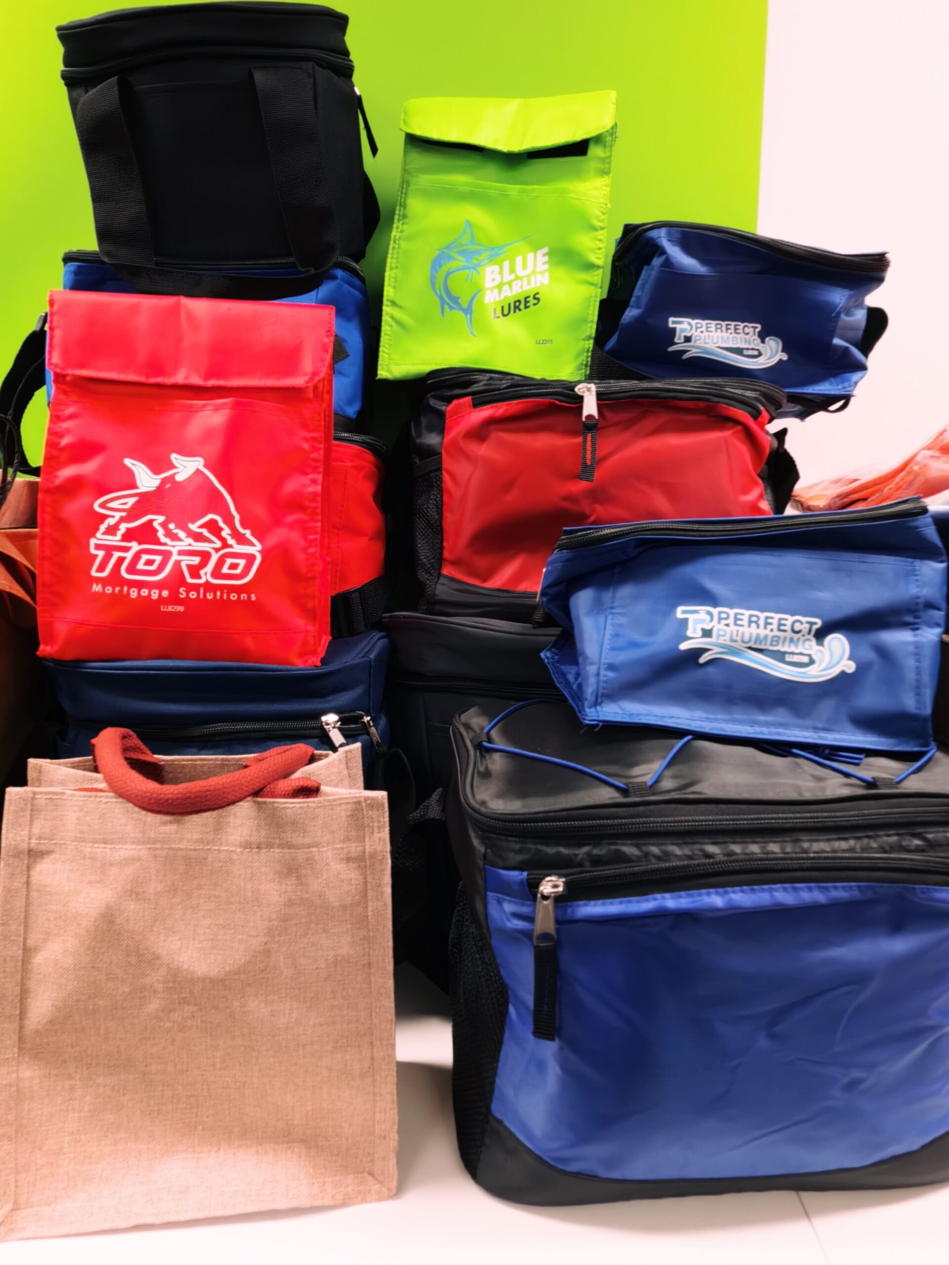 Stack of colorful insulated lunch bags and a tote bag in a vibrant showroom display.