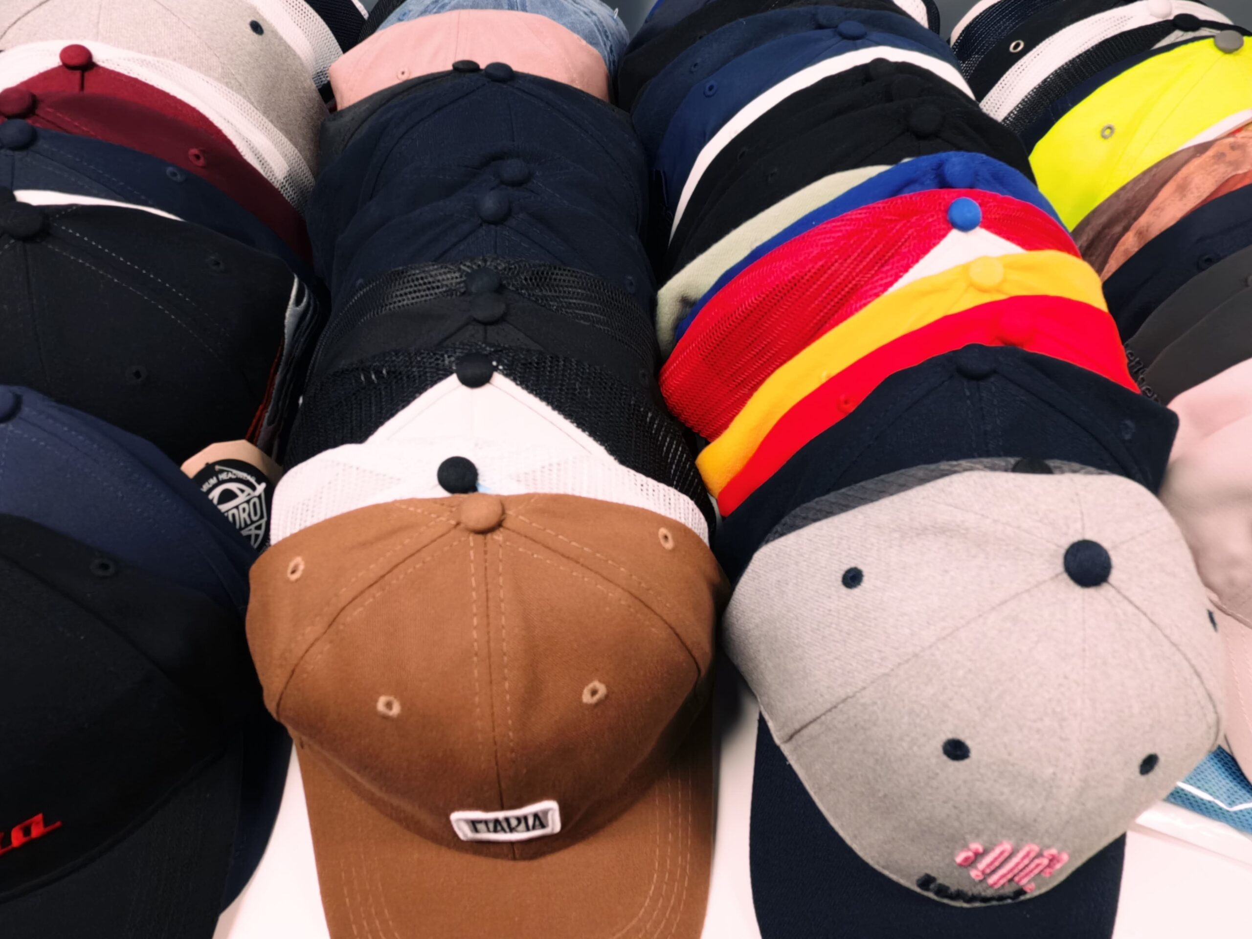 Rows of colorful baseball caps displayed on a showroom flat surface.