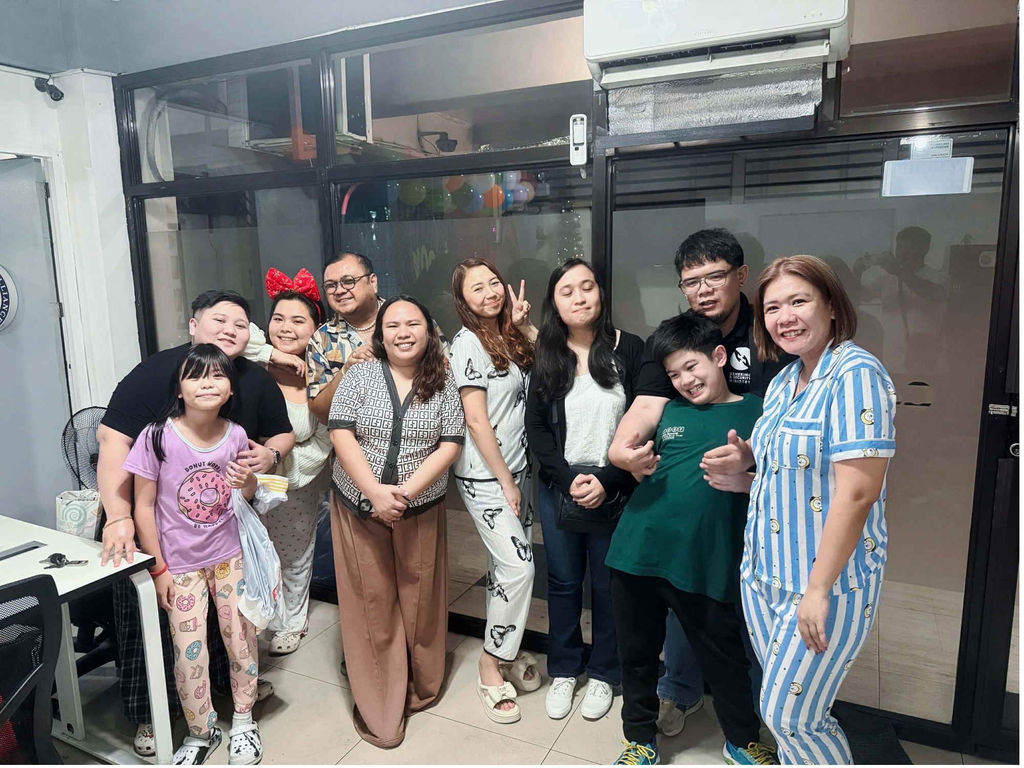 A group of ten people smiling indoors in pajamas, celebrating a fun holiday break together.