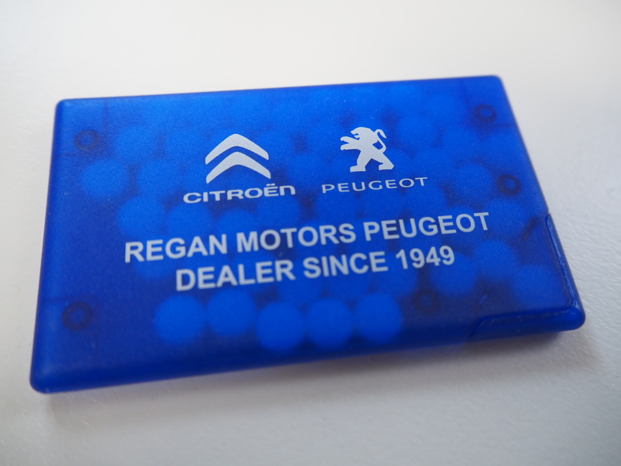 Blue case with Citroën, Peugeot logos and Regan Motors Peugeot Dealer Since 1949 text.