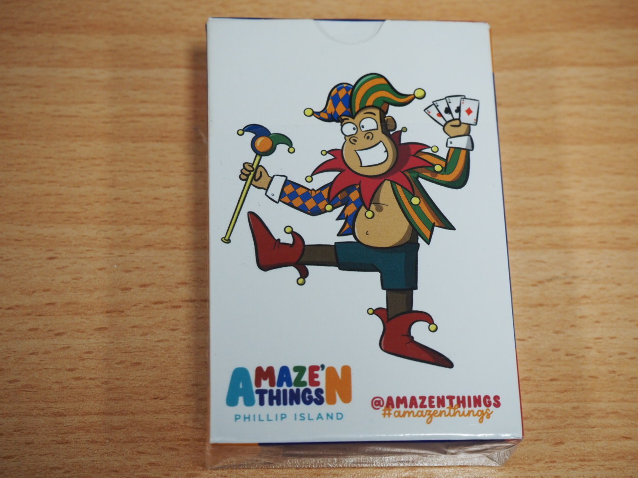 Cartoon jester with cards and staff on Amaze'n Things Phillip Island playing cards box.