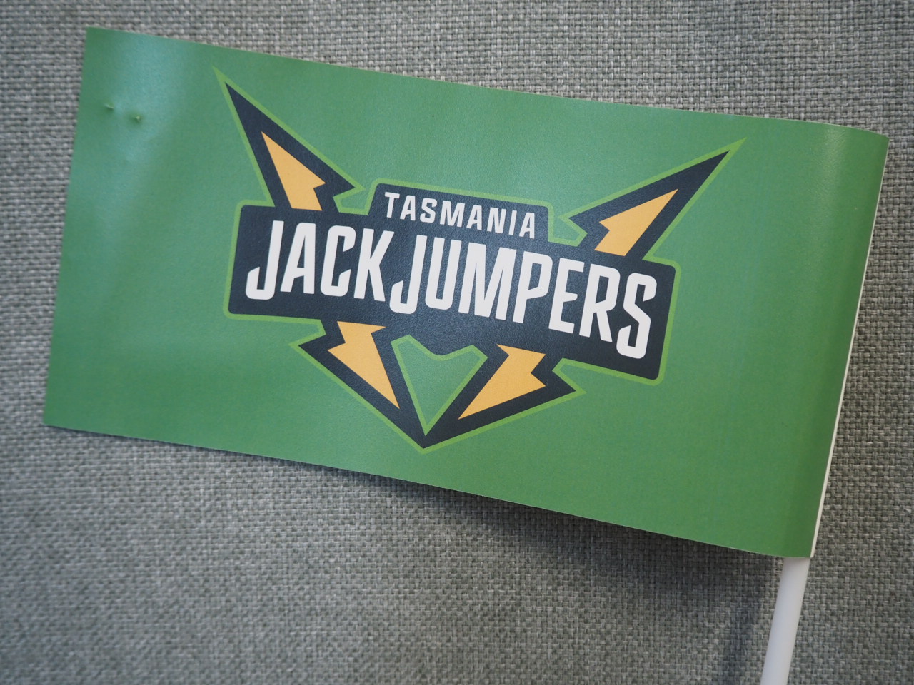 Green flag with Tasmania JackJumpers logo on a grey textured client story background.