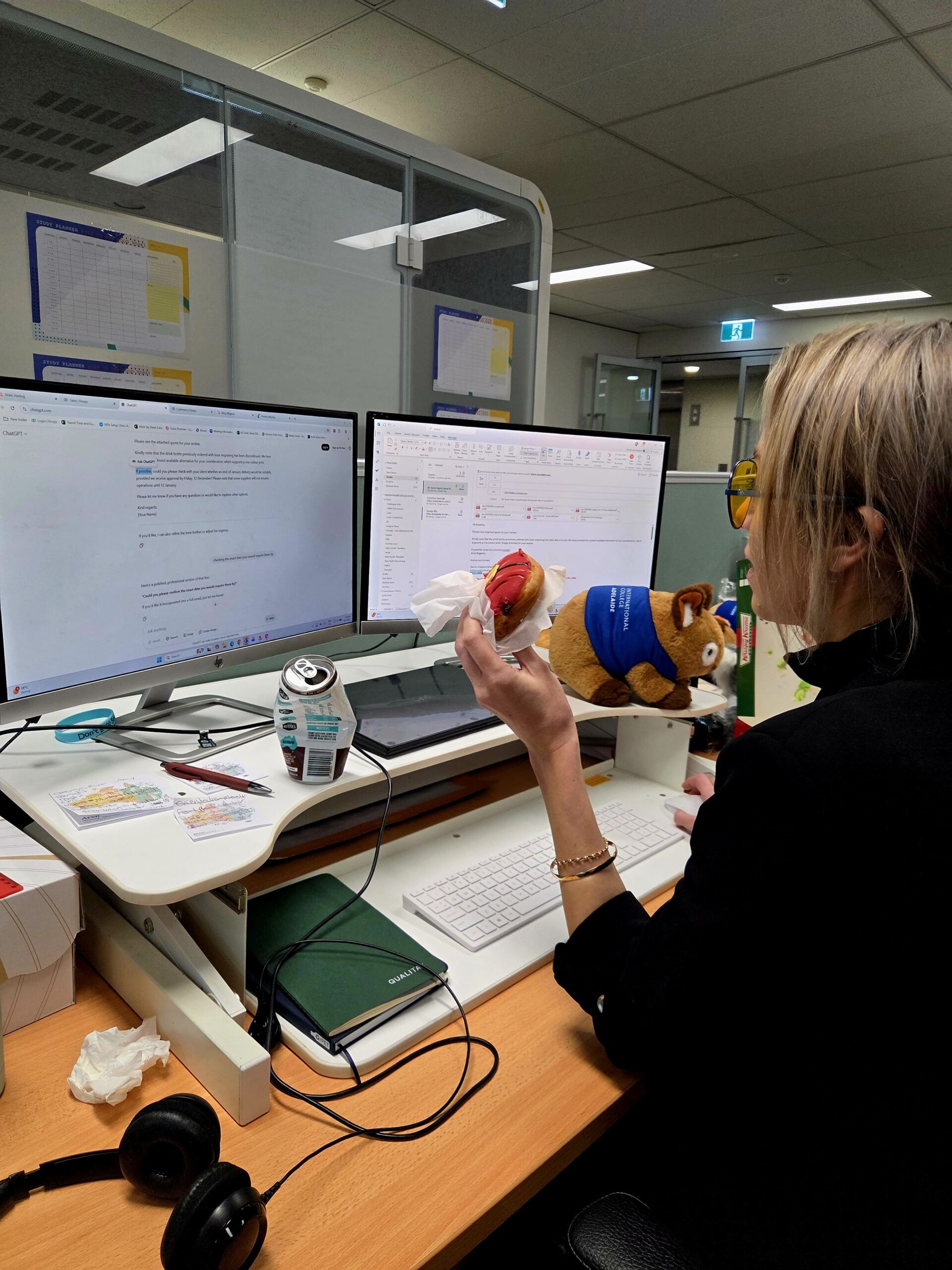 Person at a desk holding a plush dog, working at dual monitors for a promotional products supplier.