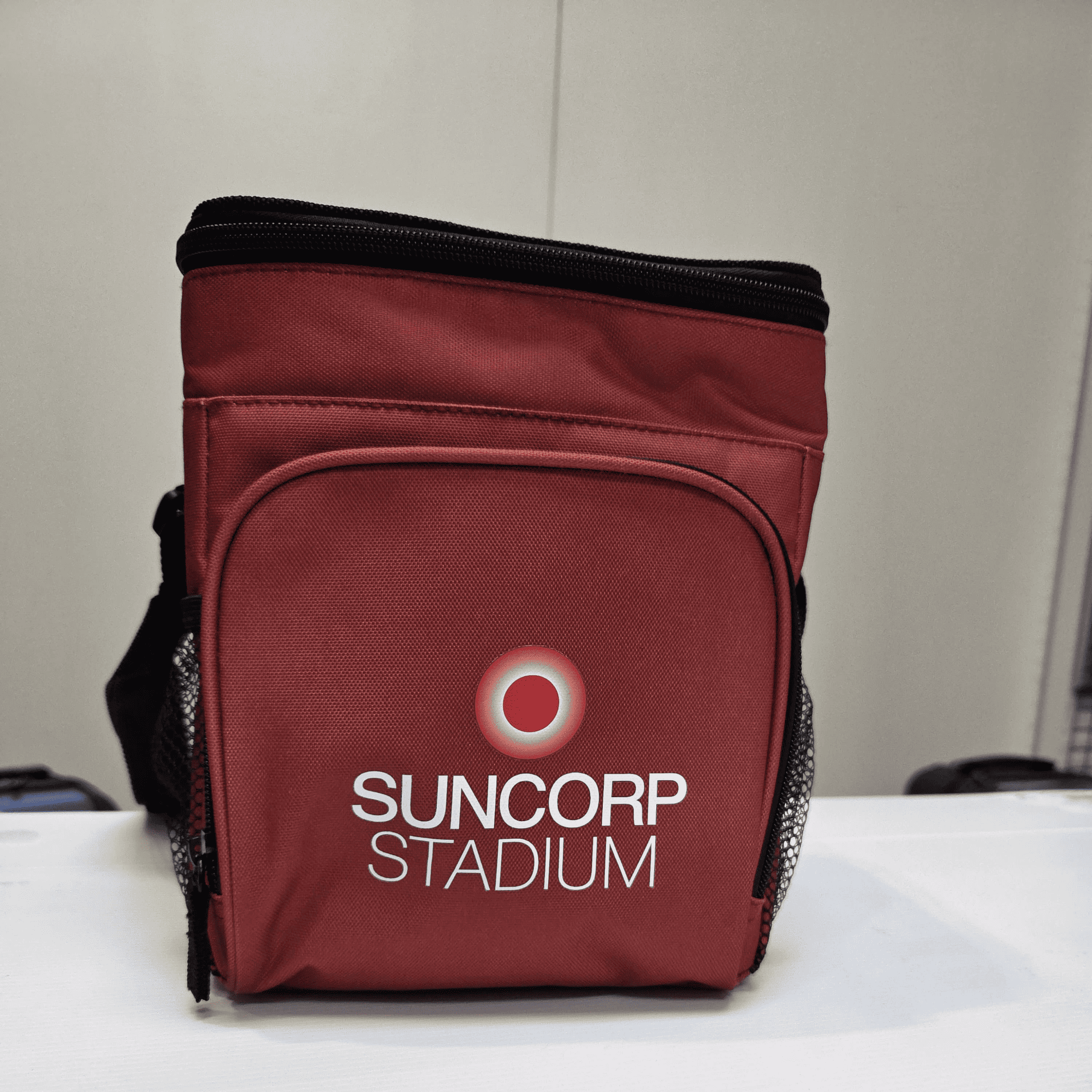 Red insulated lunch bag with Suncorp Stadium branding on the front pocket.
