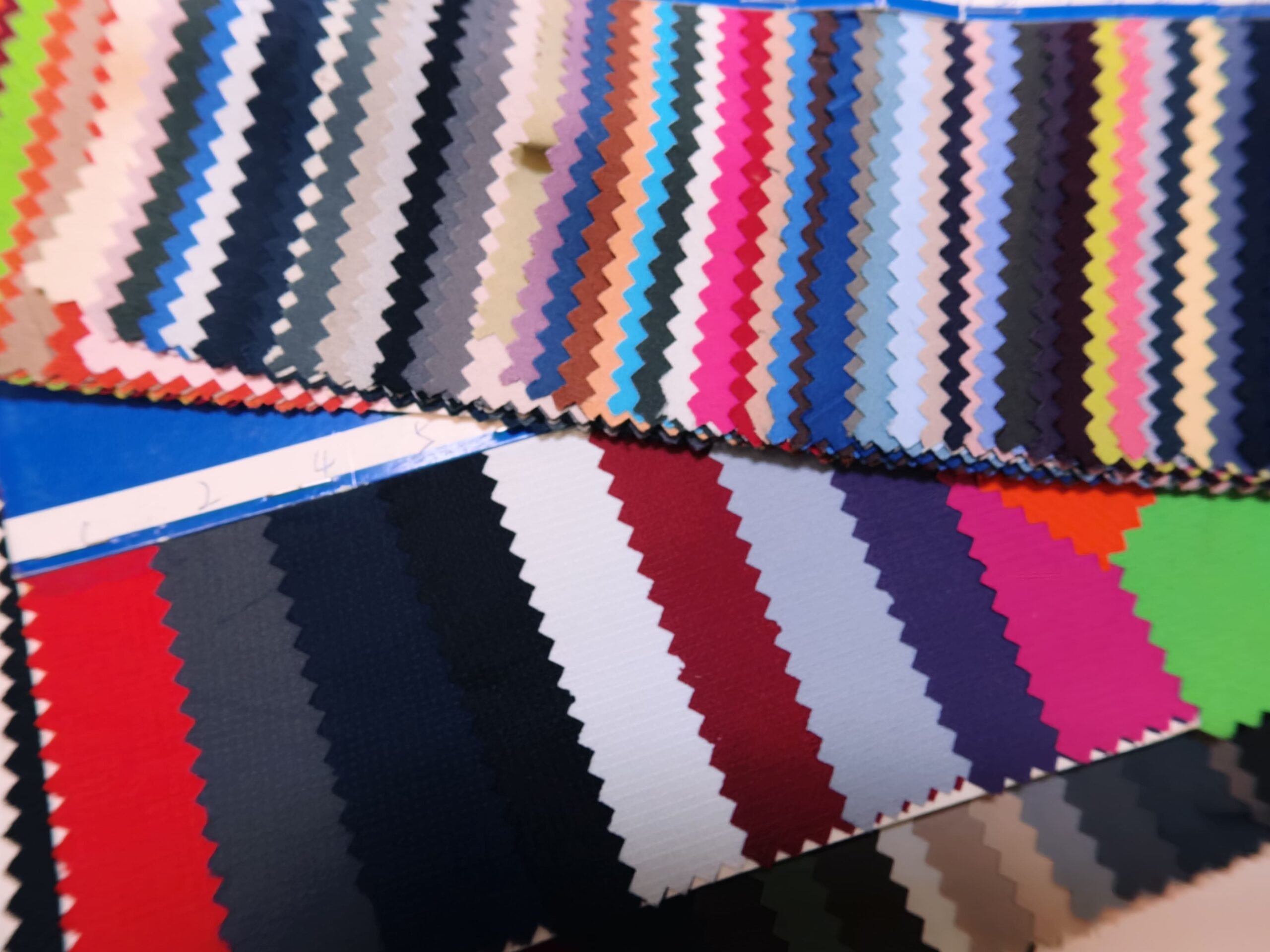 Rows of colorful fabric swatches with zigzag edges, arranged side by side in a showroom.