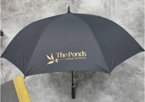 Black golf umbrella printed with The Ponds High School logo in gold on the canopy.