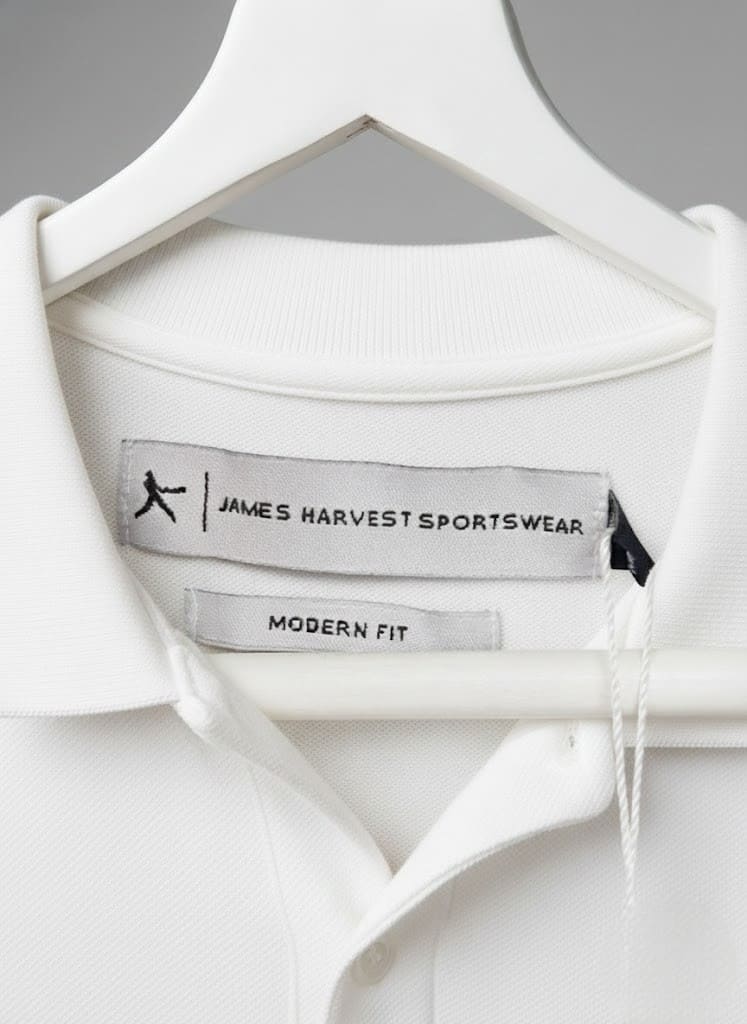 Close-up of a white polo shirt on a hanger from leading clothing brand James Harvest Sportswear.