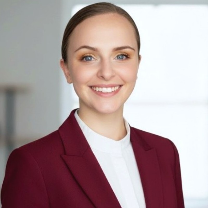 Meet the team: Woman in a maroon blazer smiling, hair pulled back, in a bright indoor setting.