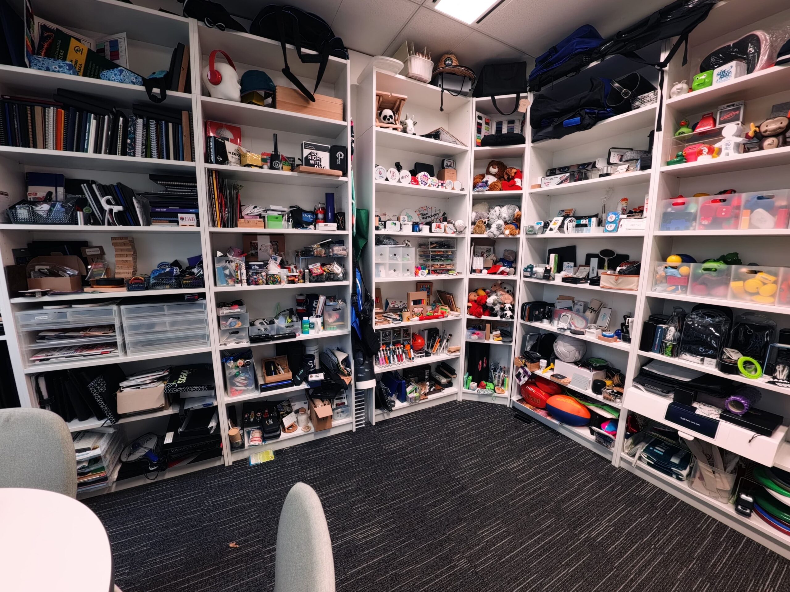Shelves in a showroom filled with assorted items, books, toys, and office supplies.