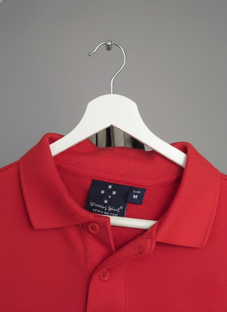 Red polo shirt from top clothing brands on a white hanger against a plain gray background.