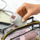 Hand placing a U&C Contemporary container into a clear pouch with a yellow zipper.