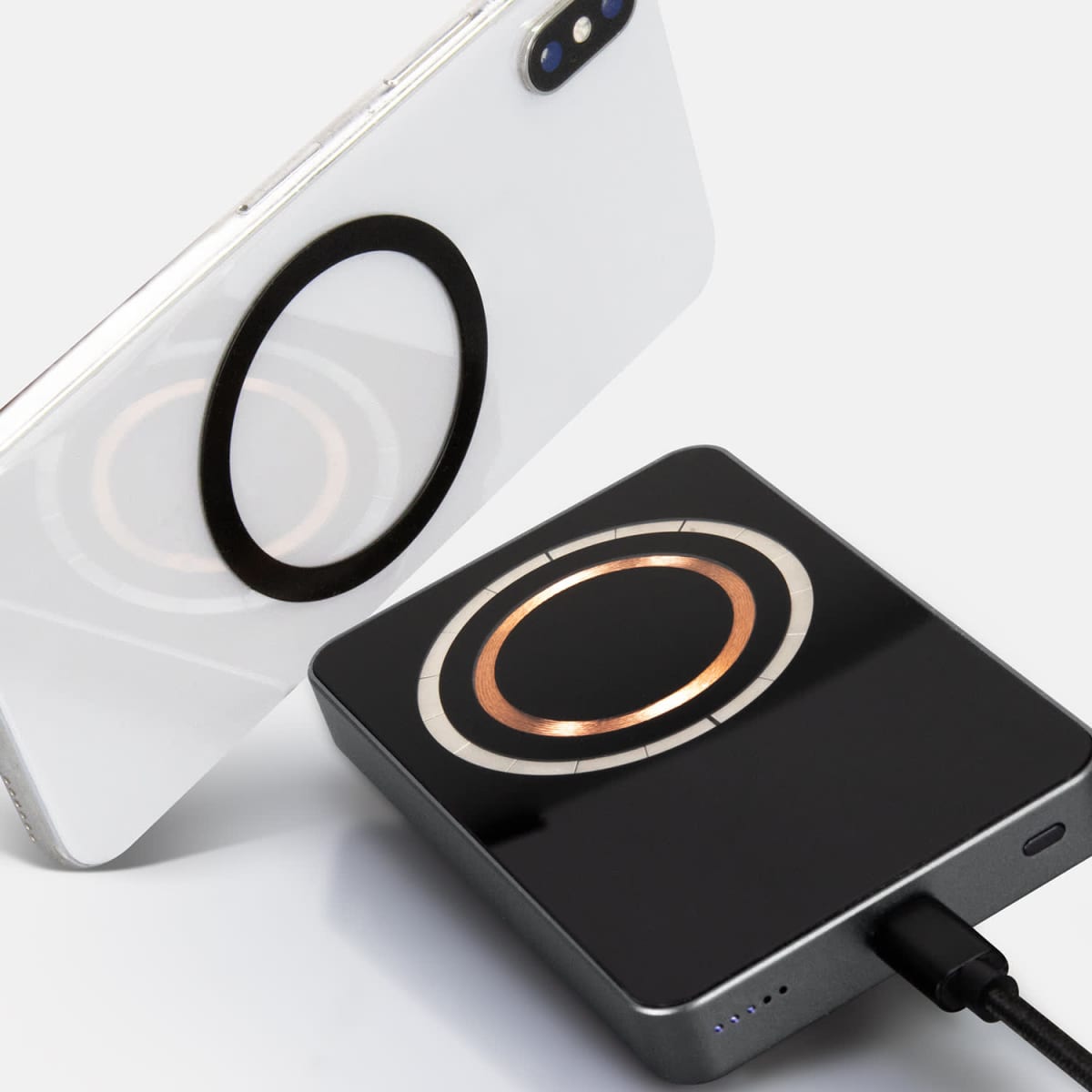 A smartphone and a wireless charging pad with circular magnetic alignment rings.
