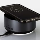 Smartphone wirelessly charging on a round black charging dock with power indicator showing 69%.