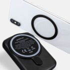 Black wireless charger and a smartphone with a circular charging pad on its back.