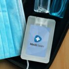 A blue face mask and Mediclean sanitizer spray on a black case.