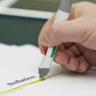 Hand highlighting the word Deflation on a printed document with a yellow marker.