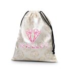 White drawstring bag with pink JEWELRY text and gem illustrations on the fabric.