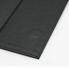 Close-up of a black, rectangular object with crease lines on a white surface.