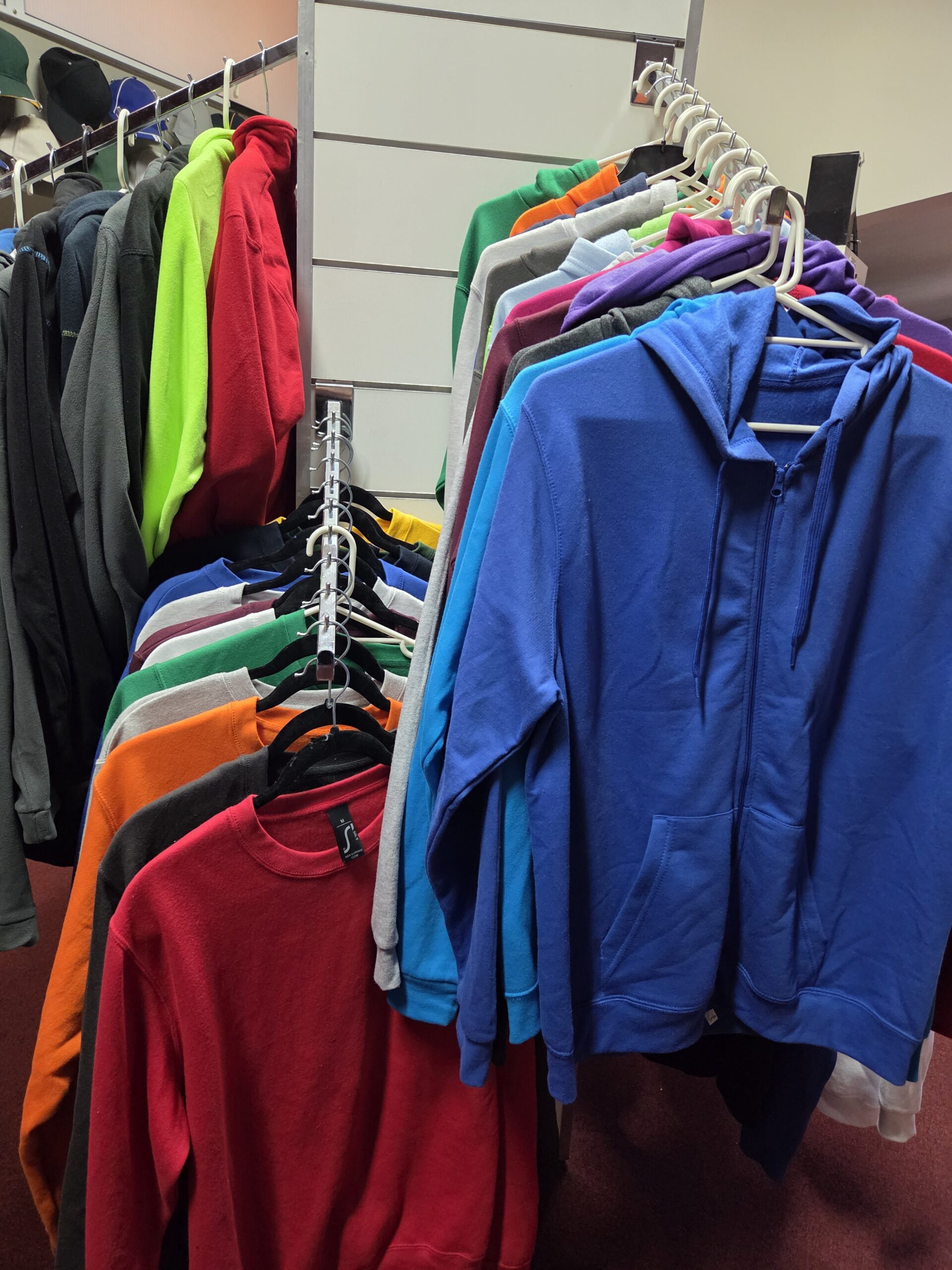 A rack of colorful hoodies and sweatshirts highlights merchandise trends 2026.