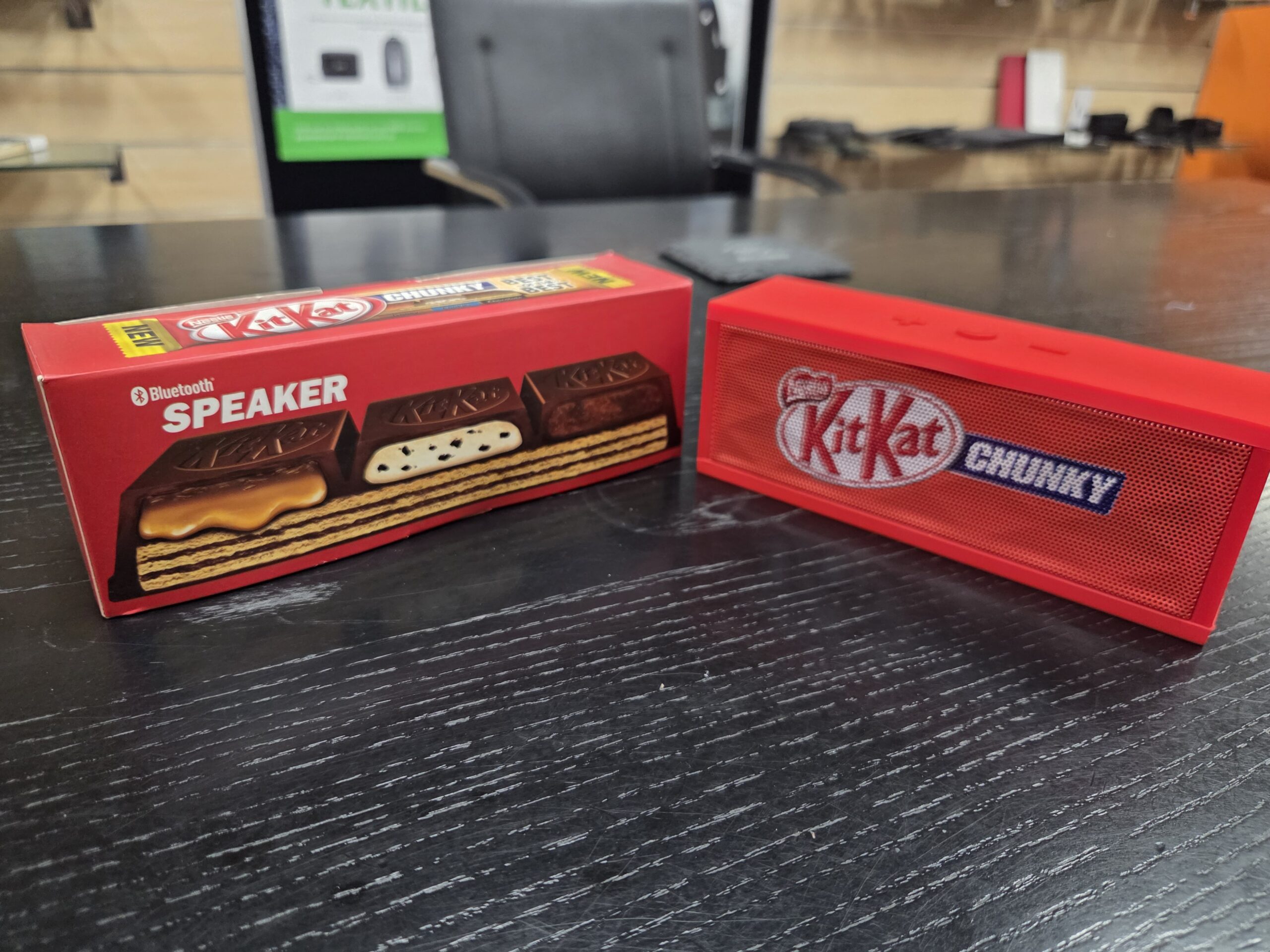 A Product sourcing Kit Kat-themed Bluetooth speaker sits by a Chunky bar box on the table.