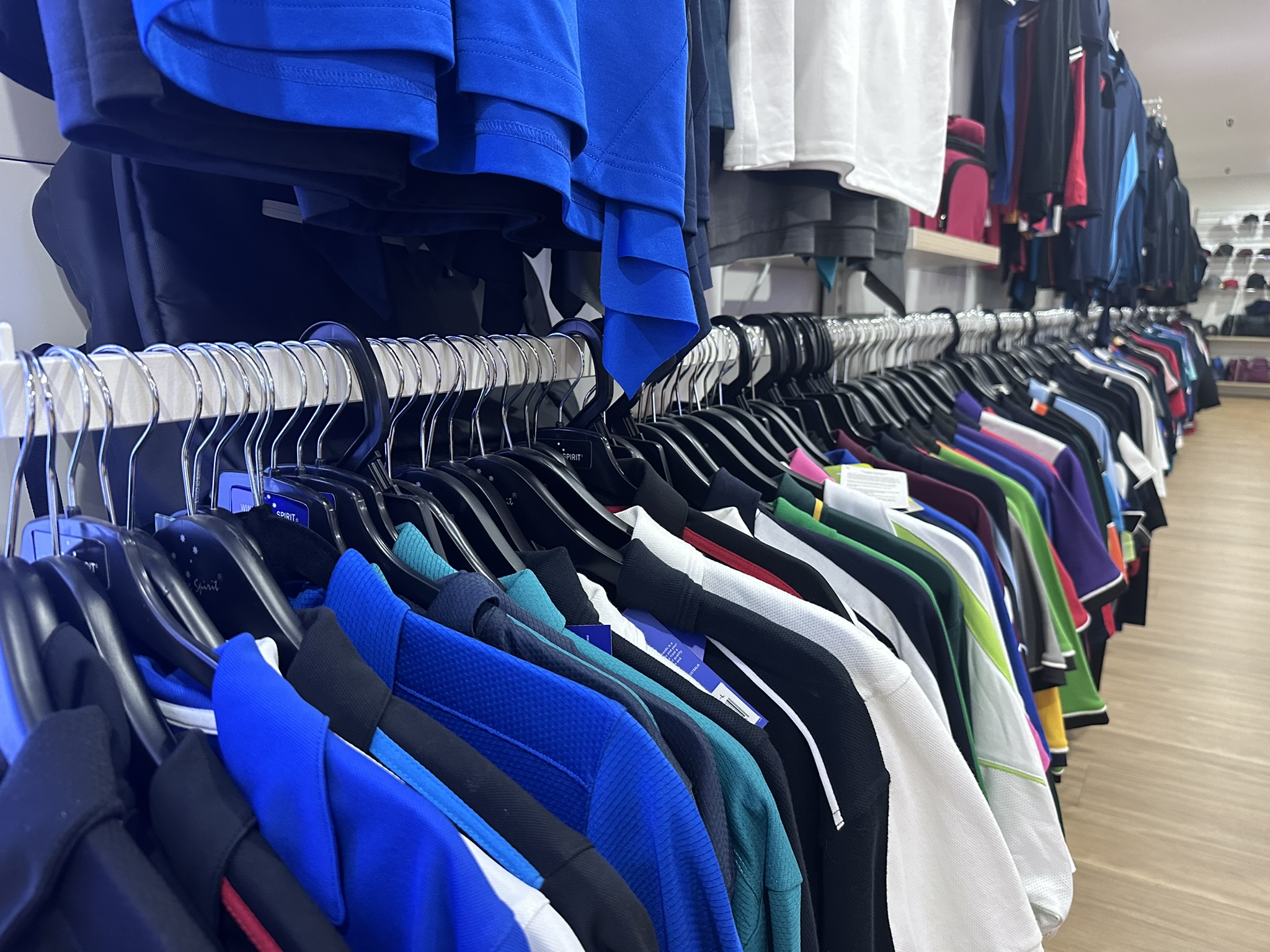 Colorful uniforms hang on a rack, showcasing quality fabrics for Aussie organisations.