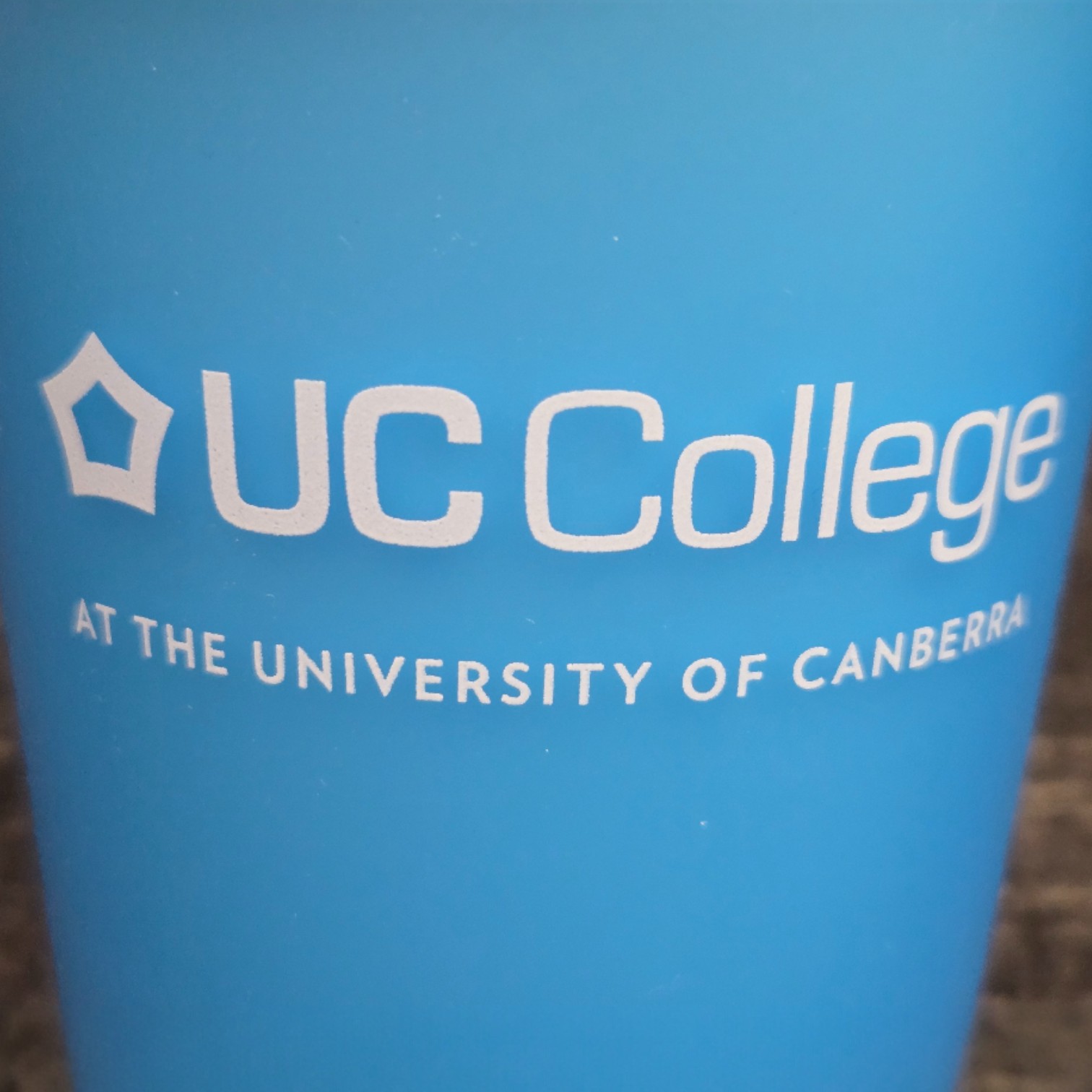 Blue cup with white text reading UC College, highlighting print colour accuracy.