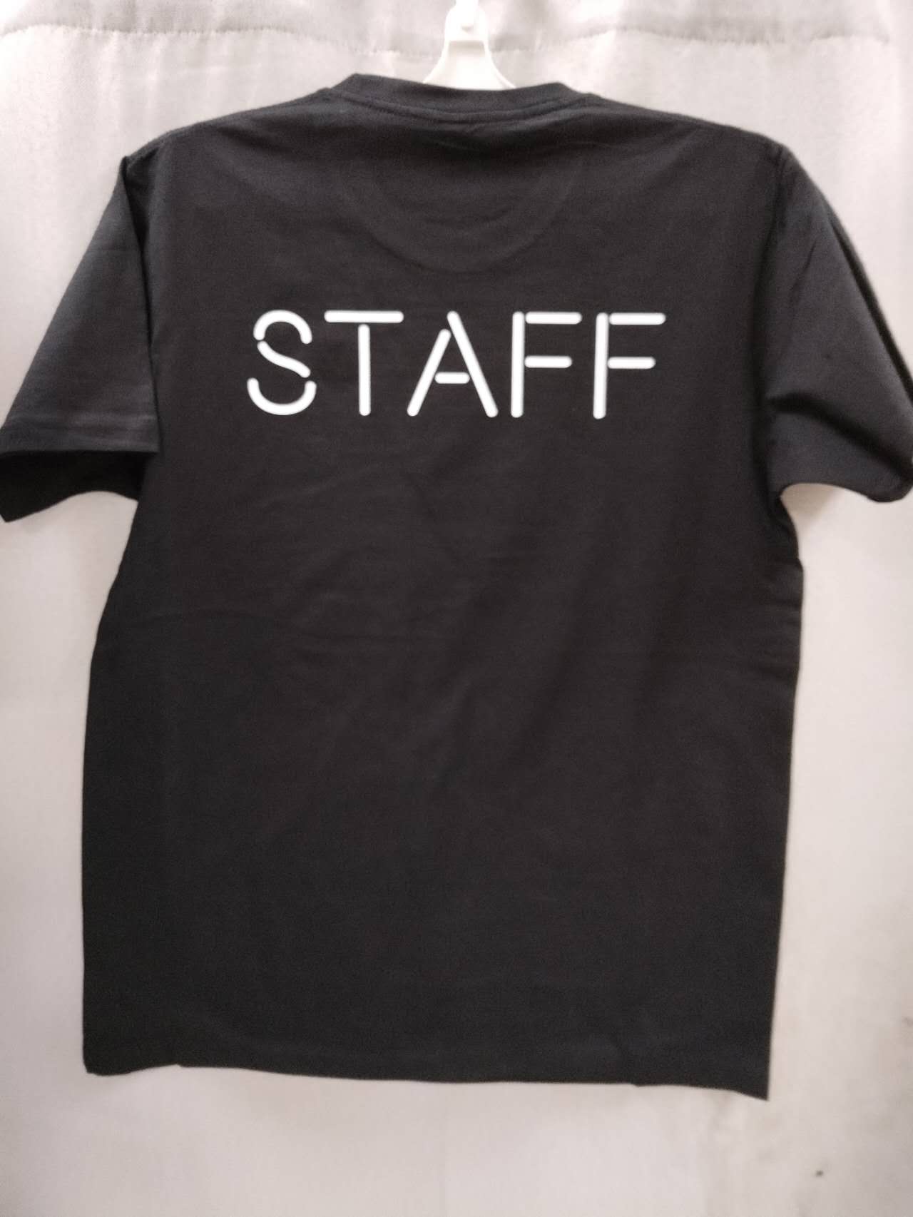 Black t-shirt with "STAFF" in bold white, showcasing screen printing vs embroidery styles.