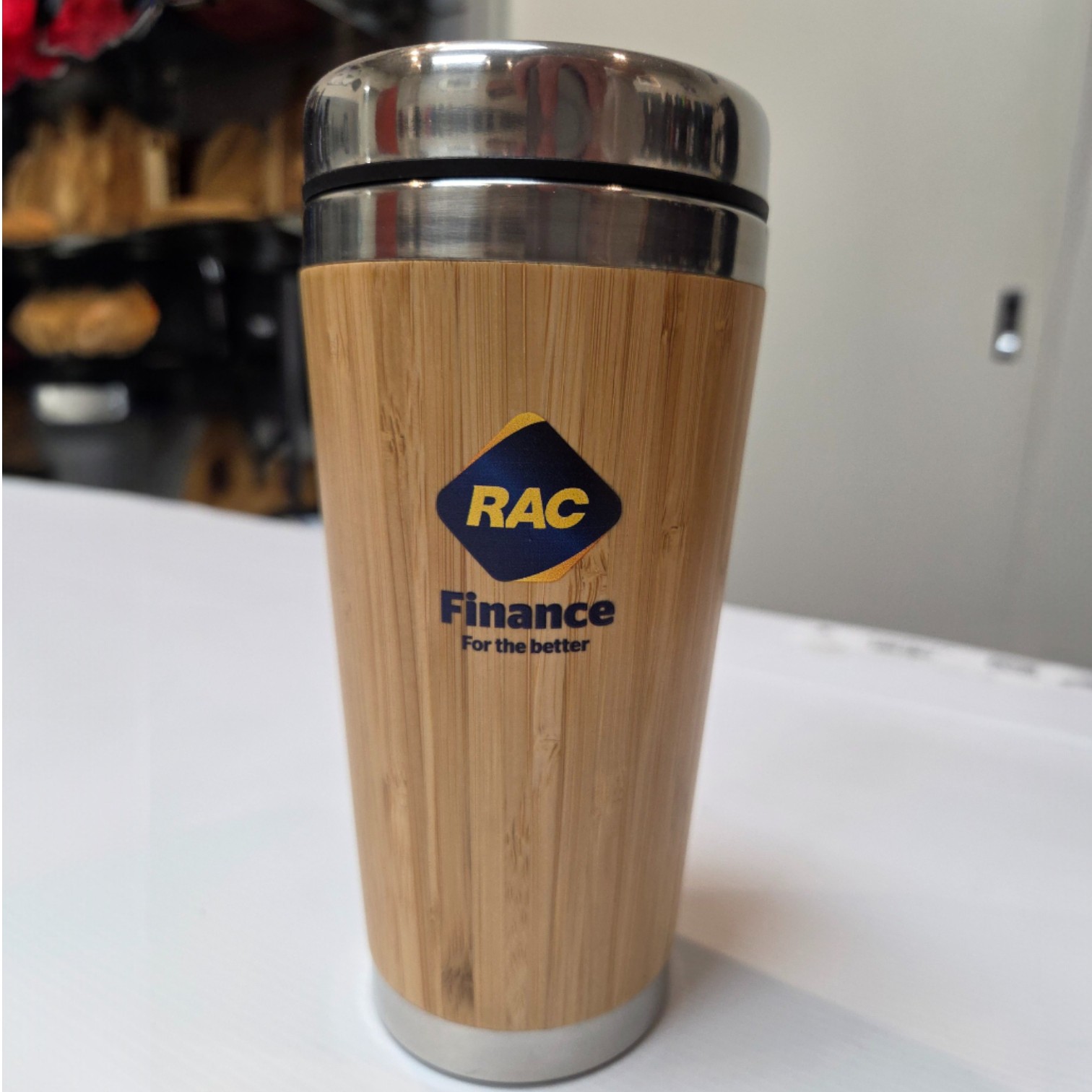 Reusable bamboo travel mug with RAC Finance logo, eco-friendly vs plastic promotional items.