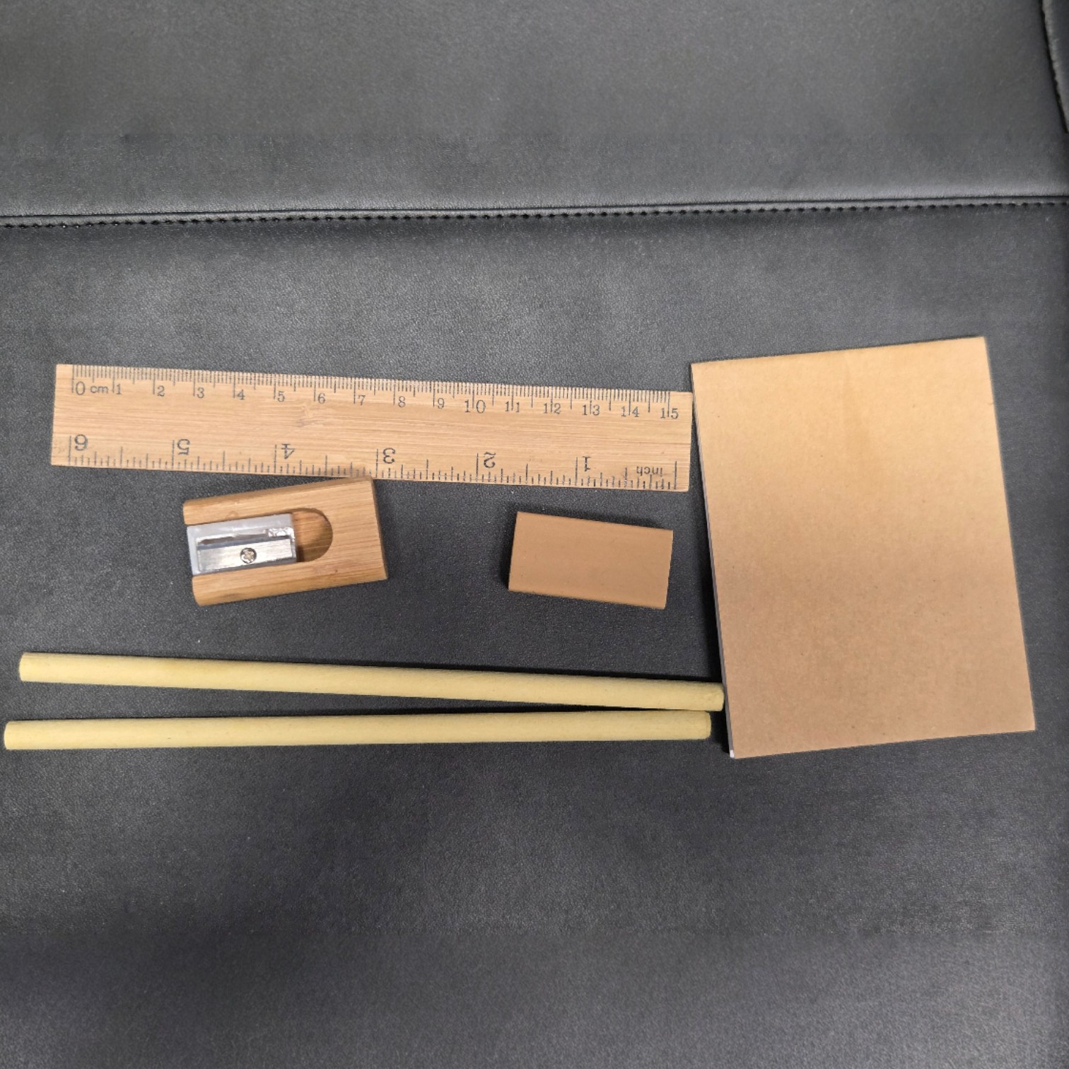 Bamboo vs plastic promotional items: Wooden ruler, sharpener, eraser, pencils, and notepad.