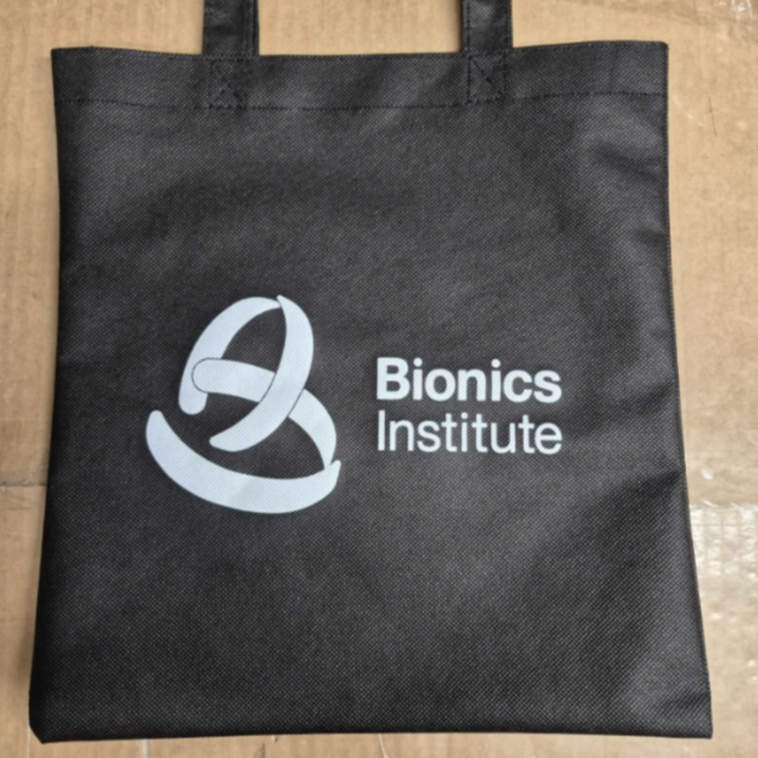 Black tote bag with Bionics Institute logo, inspired by merchandise trends 2026.