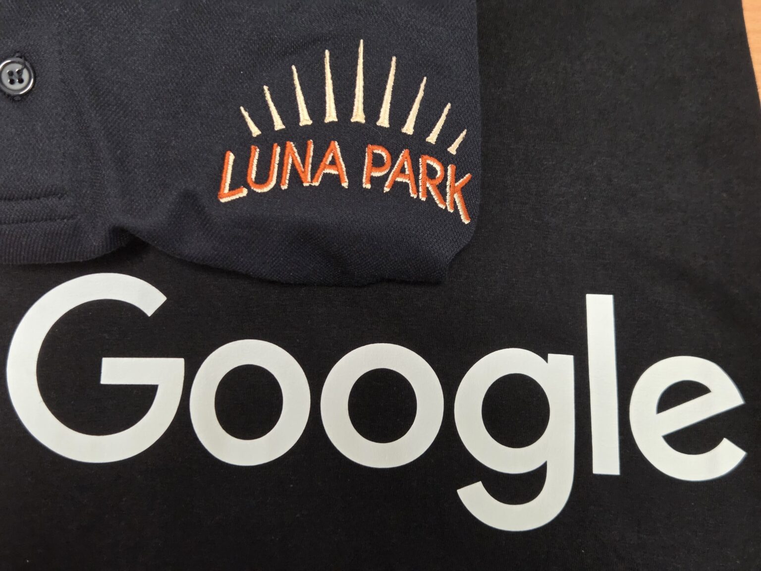 Black fabric with Google in white, LUNA PARK above in orange-yellow embroidery vs screen printing.