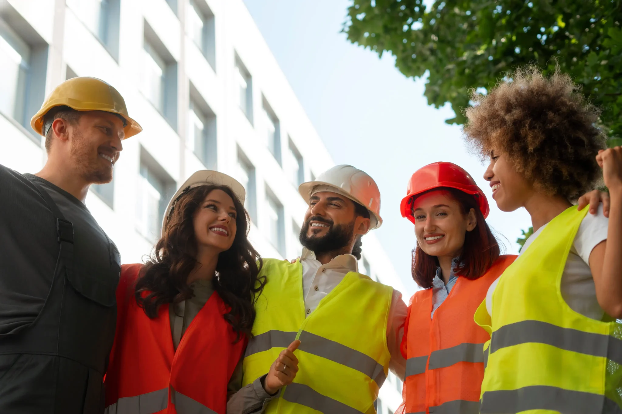 Five construction workers in safety gear smiling, standing together and showing off online merch.