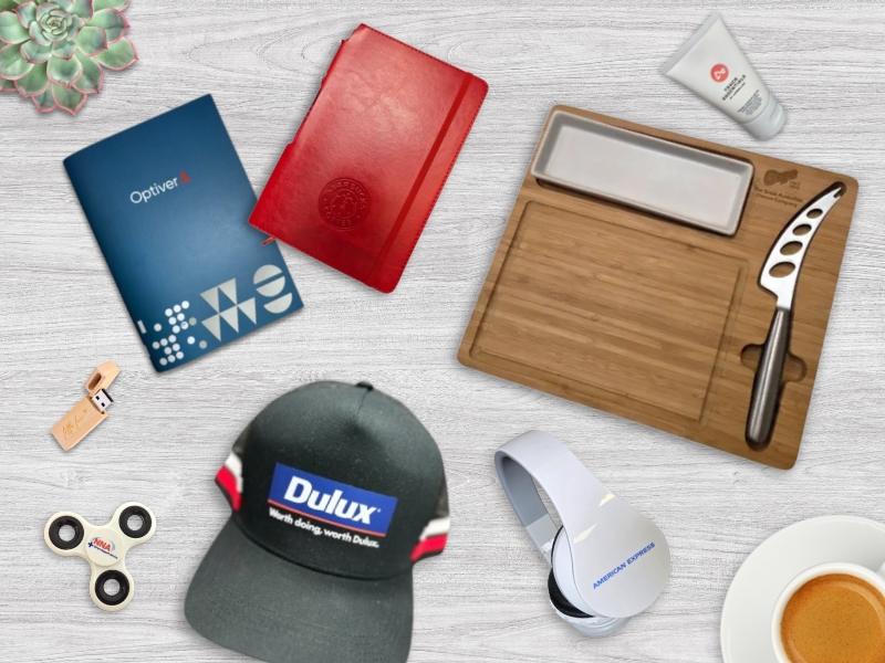 Assorted branded office items and case studies on a white desk, including notebooks and snacks.