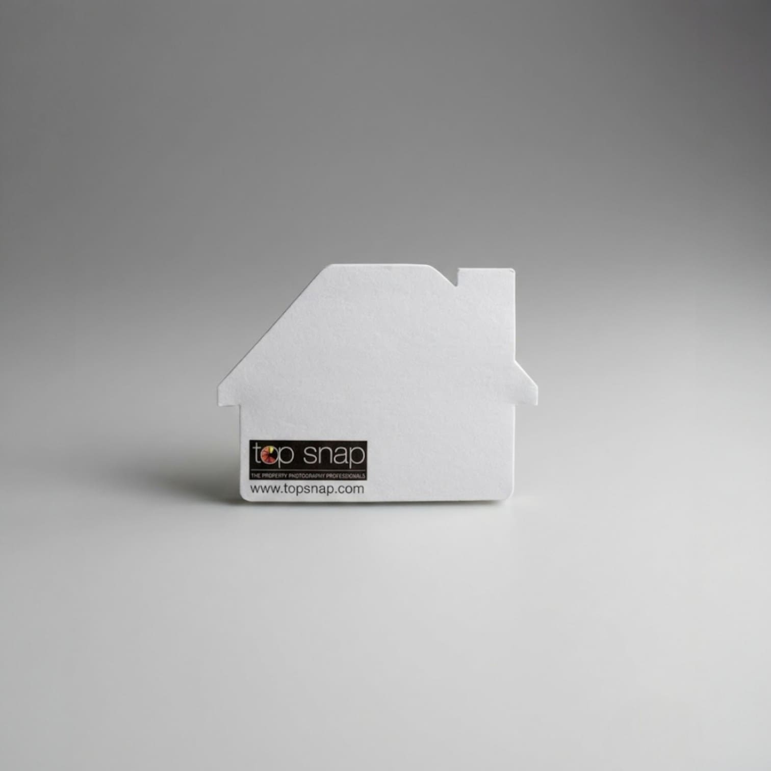 White house-shaped object with top snap label, perfect as an unusual promotional product.