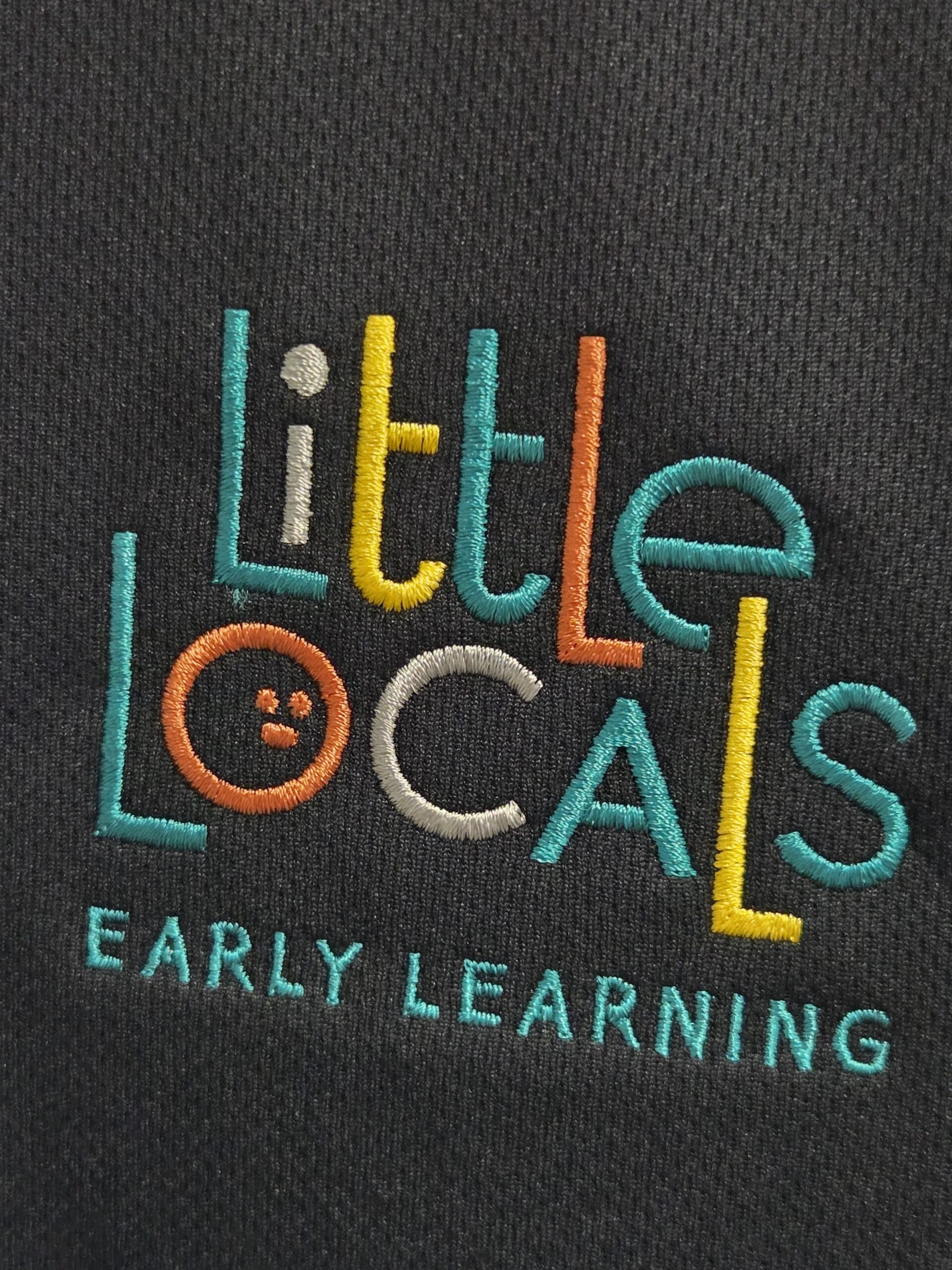 Little Locals Early Learning logo in vibrant embroidery vs screen printing on dark fabric.