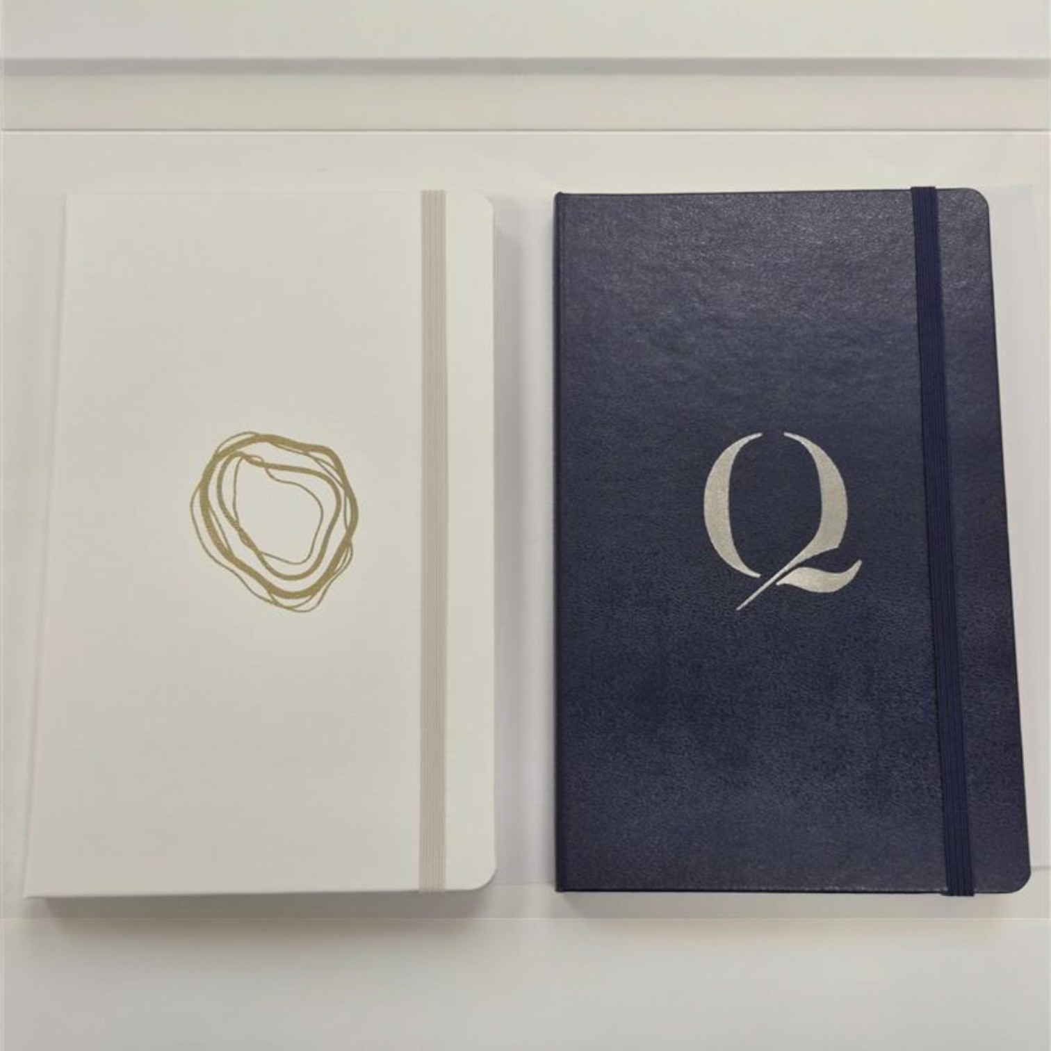 Two closed notebooks—on-trend merchandise for 2026—in stylish gold and silver designs.