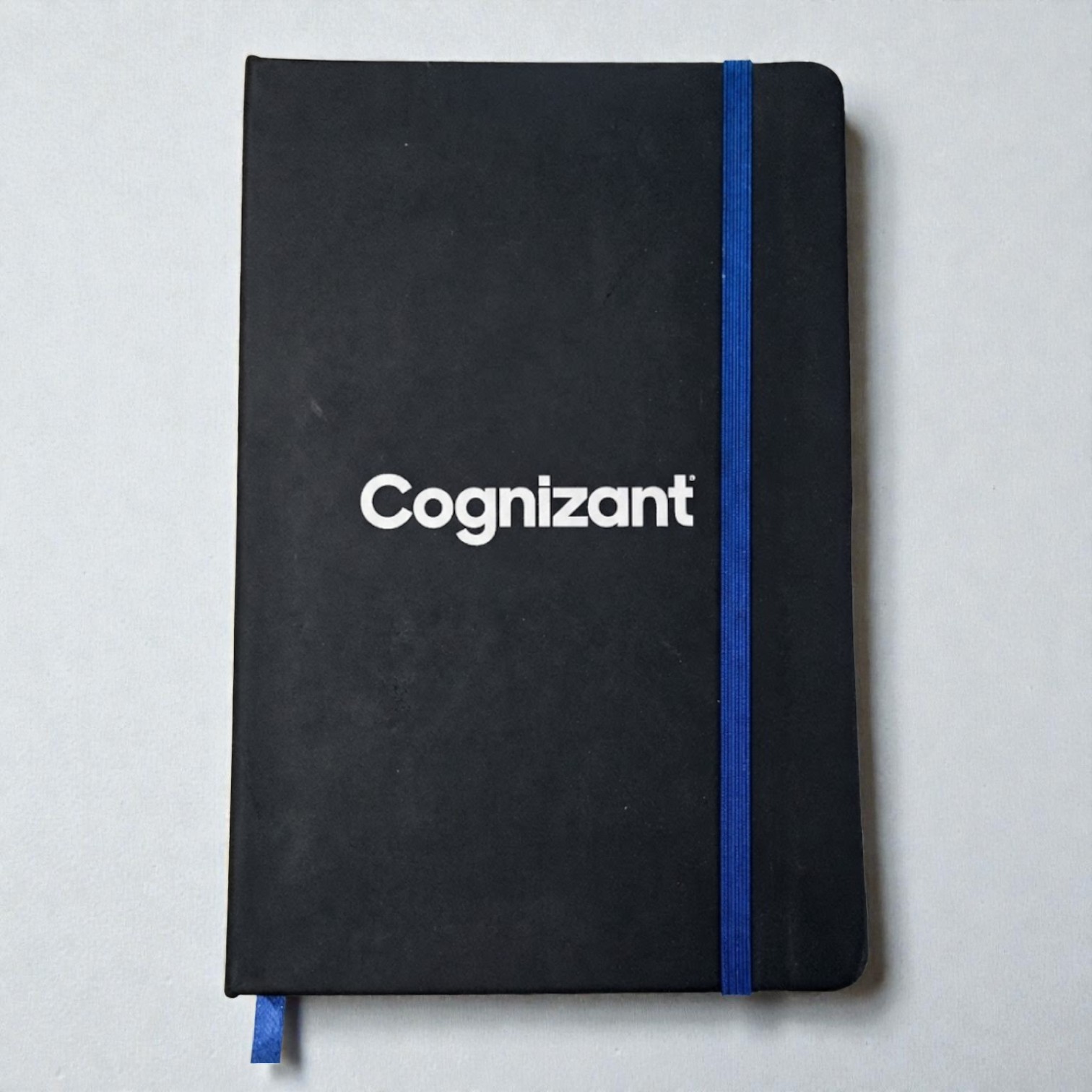 Black notebook with Cognizant text, perfect for real estate welcome packs, blue elastic band.