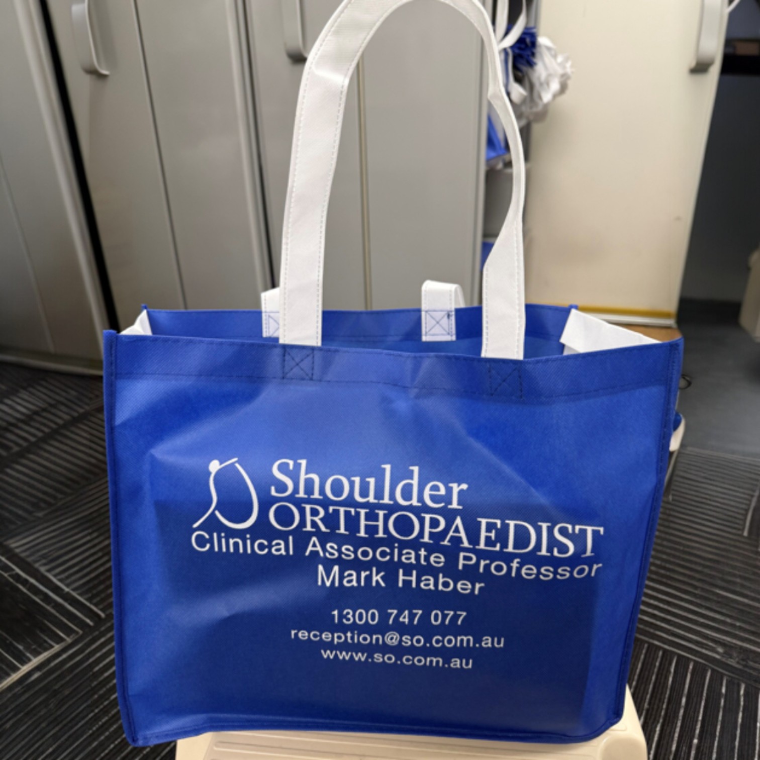 Blue tote bag featuring Shoulder Orthopaedist Mark Haber's info, inspired by product trends Sydney 2026.