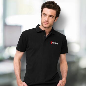 Man in custom polo shirt with a central logo stands in a blurred office setting.