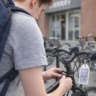Person locking a bike outside, Aloe Nursery tag and Clink Budget Key Rings on handlebars.